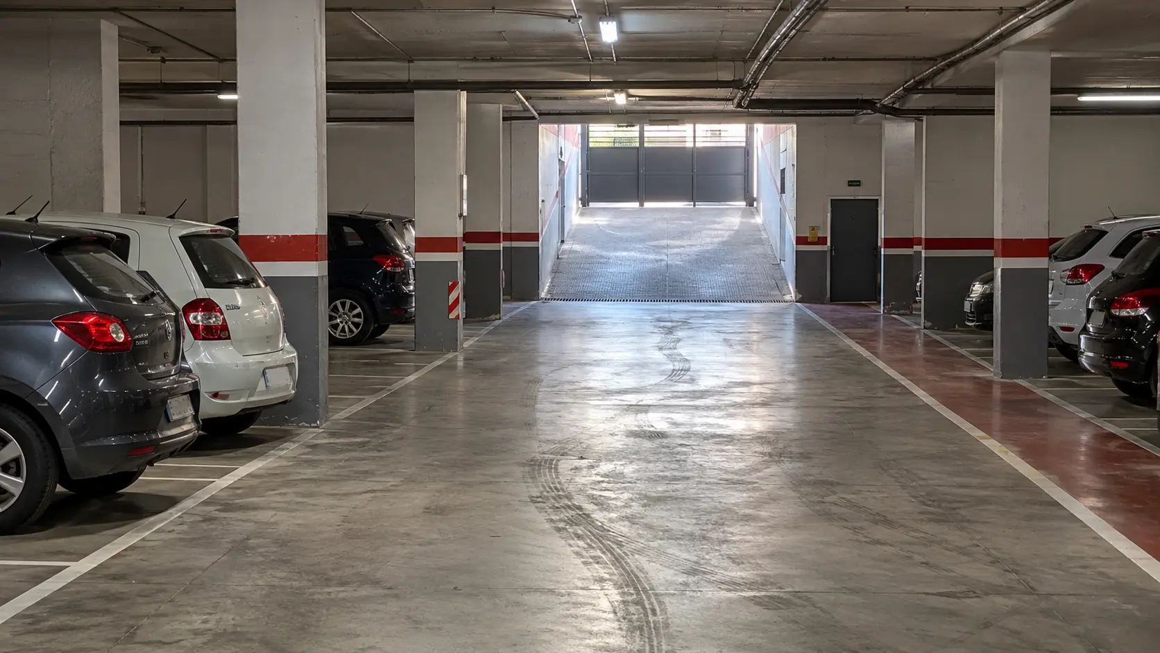 Garaje comunitario con plazas de aparcamiento, recorrido peatonal y acceso de vehículos.